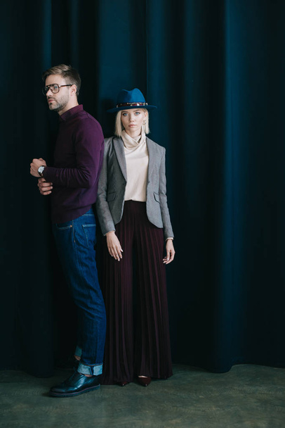 full length view of stylish young man in glasses and blonde woman in hat near curtain - Photo, Image