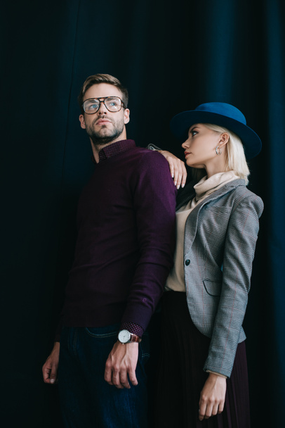 stylish young man in glasses and blonde woman in hat near curtain - Foto, Imagen