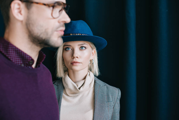 cropped view of stylish young man in glasses and blonde woman in hat near curtain - Фото, изображение