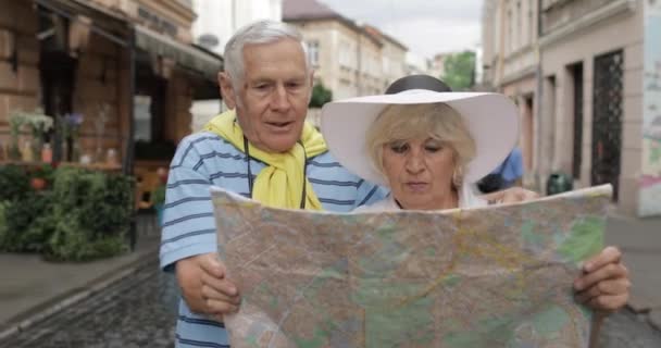Senior férfi és női turisták álló térképet a kezében keres útvonalat - Felvétel, videó