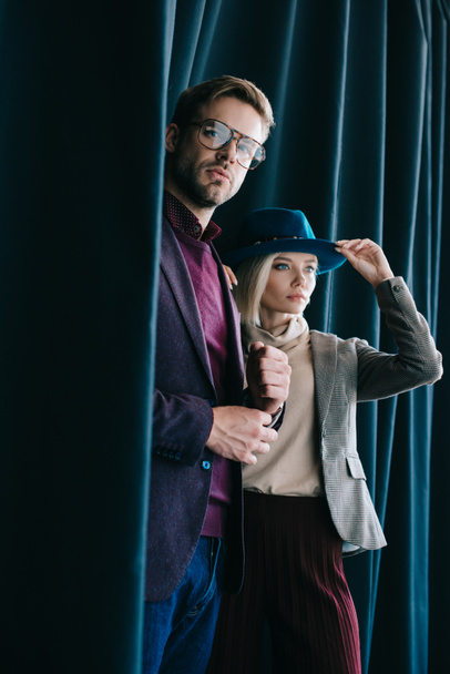 stylish young man in glasses and blonde woman in hat near curtain - Photo, Image