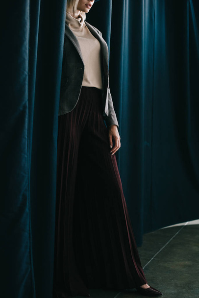 vue recadrée de femme élégante en pantalon palazzo debout près du rideau
 - Photo, image