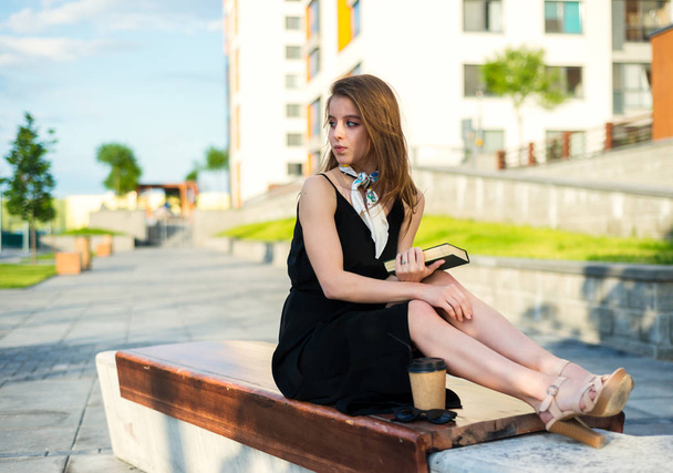 Very beautiful young woman with a book outside - Foto, afbeelding