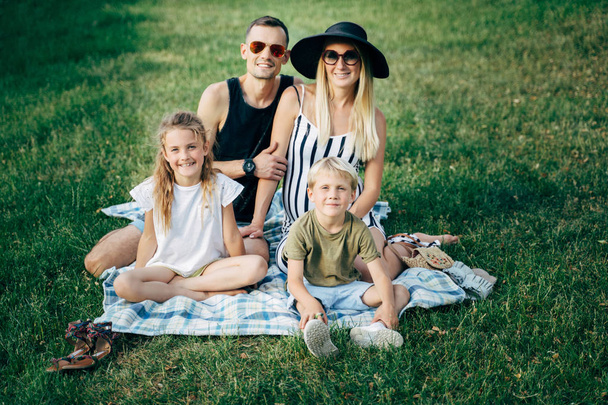 Photo d'une jeune famille avec des enfants assis sur un pique-nique le jour de l'été
 - Photo, image
