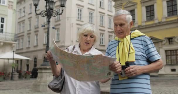 Ηλικιωμένοι άνδρες και γυναίκες τουρίστες περπάτημα με ένα χάρτη στα χέρια που αναζητούν διαδρομή - Πλάνα, βίντεο