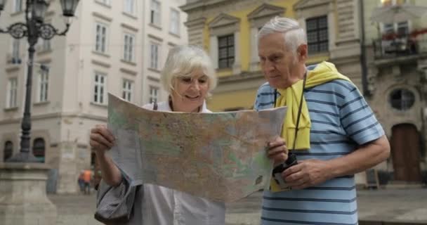 Turistas senior masculinos y femeninos caminando con un mapa en las manos buscando ruta
 - Metraje, vídeo