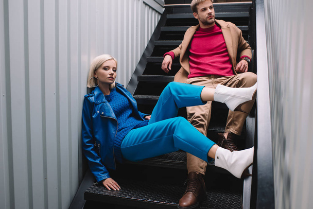 stylish young woman and man in autumn clothes sitting on stairs - Fotografie, Obrázek