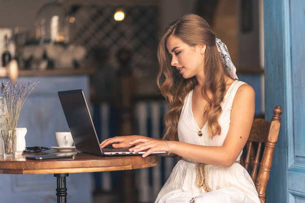 Mujer joven sentada en la cafetería trabajando en el ordenador portátil
 - Foto, Imagen