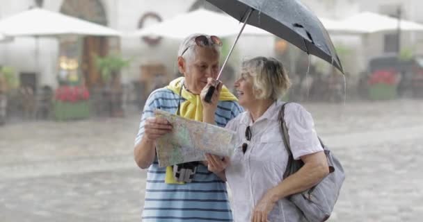 Senior turisteja sateinen sää seistä ja etsivät reittiä kartalla
 - Materiaali, video