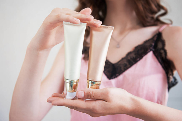 manos femeninas sosteniendo tubos de crema cosmética
. - Foto, imagen
