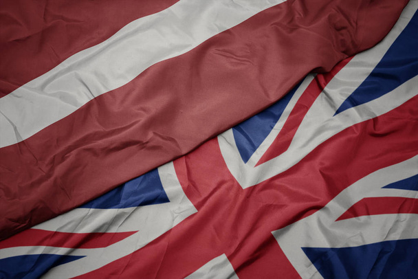Nagy-Britannia és Lettország nemzeti zászlója színes zászló hullámzó. - Fotó, kép