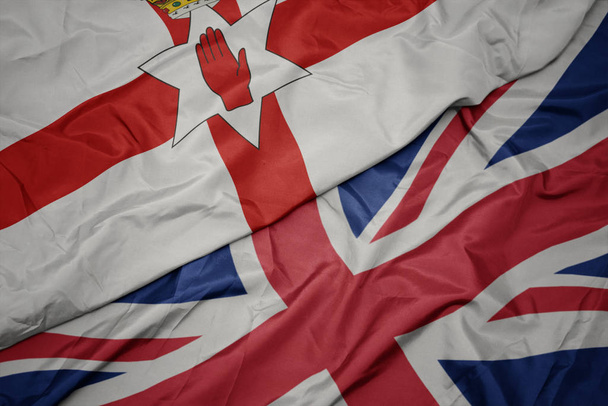 falujące kolorowe flagi Wielkiej Brytanii i flagi narodowej Irlandii Północnej. - Zdjęcie, obraz