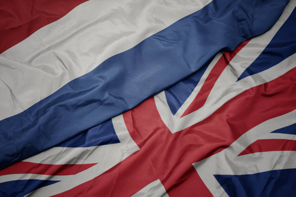 ondeando colorida bandera de Gran Bretaña y bandera nacional de los Países Bajos
. - Foto, imagen