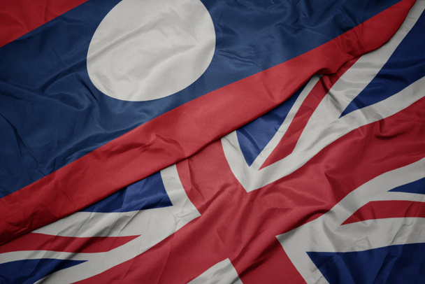 ondeando colorida bandera de Gran Bretaña y bandera nacional de laos
. - Foto, imagen