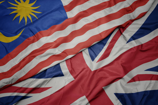 sventolando bandiera colorata di Gran Bretagna e bandiera nazionale della Malesia
. - Foto, immagini