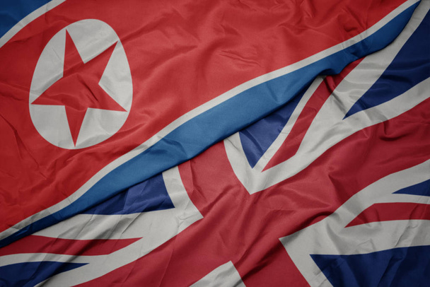zwaaiende kleurrijke vlag van Groot-Brittannië en de nationale vlag van Noord-Korea. - Foto, afbeelding