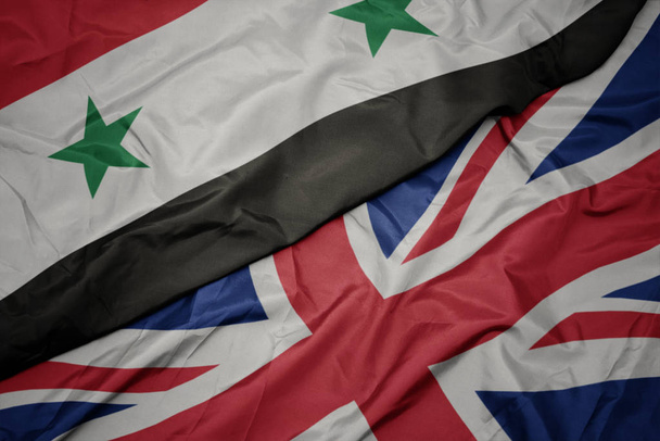 waving colorful flag of great britain and national flag of syria. - Photo, Image