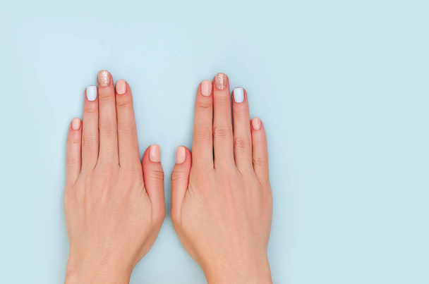 Dames handen met pastel manicure op blauwe achtergrond met Kopieer ruimte. - Foto, afbeelding