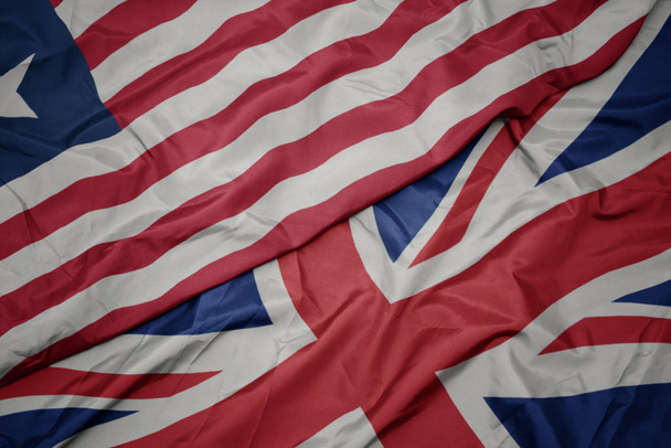 ondeando colorida bandera de Gran Bretaña y bandera nacional de Liberia
. - Foto, imagen