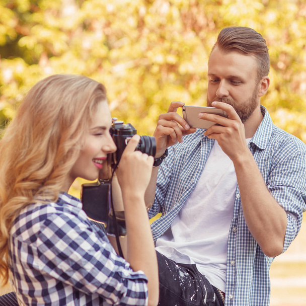 Man and woman taking photos with a camera and a smartphone in autumn park. - Foto, immagini