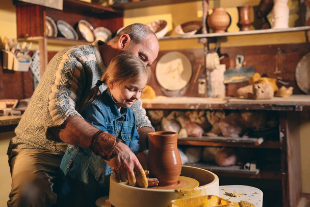 Pottery workshop. Grandpa teaches granddaughter pottery. Clay modeling - Zdjęcie, obraz