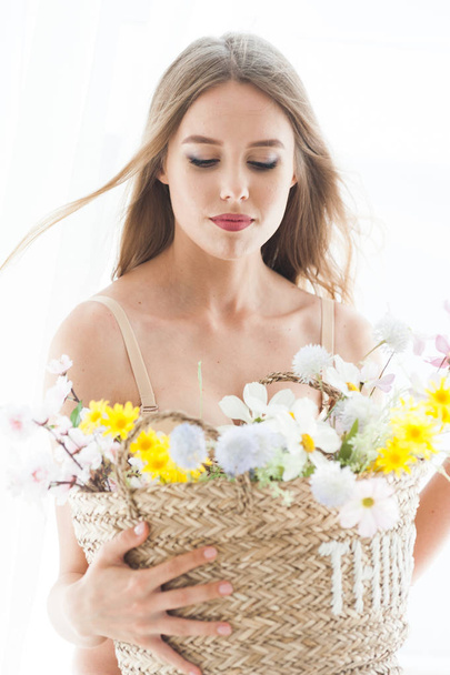 Mooie jonge blonde vrouw ondergoed poseren met bloemen.Morning bruid. - Foto, afbeelding