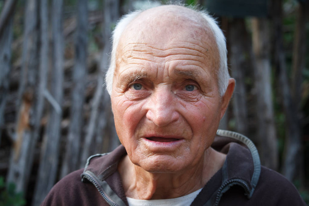Close-up portrait of a very old man against the background of wattle, selective focus - Photo, Image