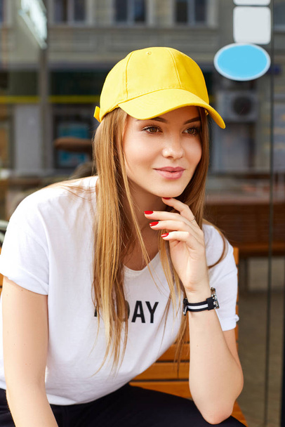 Beautiful blonde girl in a yellow cap and t-shirt - Photo, Image