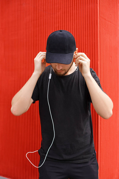 Siyah şapkalı yakışıklı adam ve kulaklıklı bir tişört - Fotoğraf, Görsel
