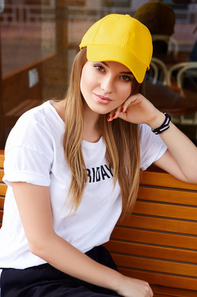 Beautiful blonde girl in a yellow cap and t-shirt - Fotó, kép