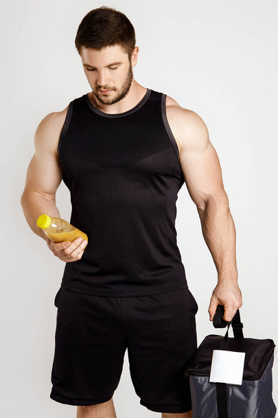 Handsome muscular man with a thermal bag and juice - Фото, зображення