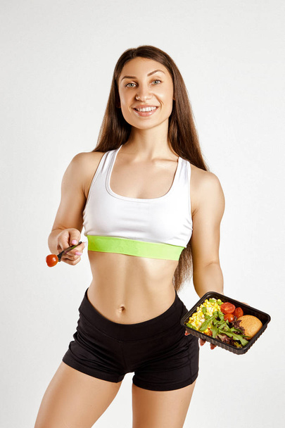 Beautiful muscular girl holds a serving of food in a box - Photo, image