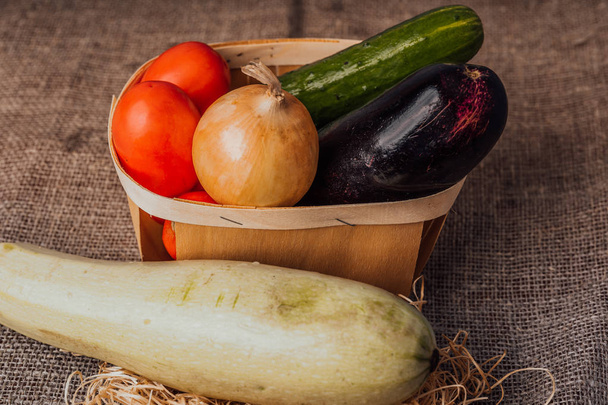 Vegetables, onions, eggplant, tomatoes and cucumbers in a basket. The concept of agriculture, healthy lifestyle, healthy eating and diet. - Photo, image