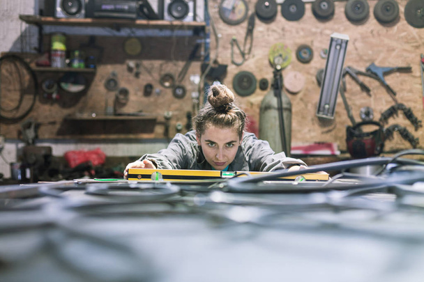young woman in a workshop measuring - Photo, image