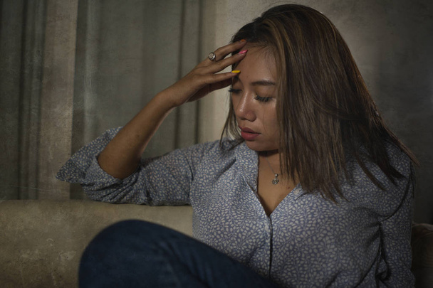 young beautiful sad and depressed Asian woman in pain thoughtful and confused at home couch feeling broken heart suffering depression crisis and anxiety problem  - Foto, Imagem