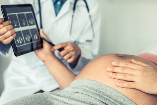 妊娠中の女性は、妊娠相談のために病院や診療所で婦人科医を訪問しています。妊娠写真を見て婦人科の概念. - 写真・画像