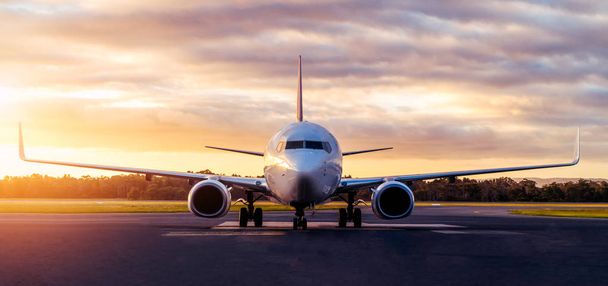 オーストラリア、タスマニア州ホバートの劇的な空の下で空港滑走路上の飛行機の夕日の眺め。航空技術と世界旅行コンセプト. - 写真・画像