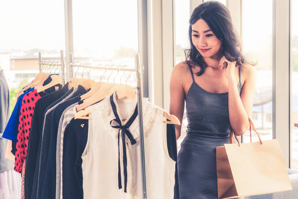 Mujer comprando ropa en una tienda de ropa en un centro comercial. Estilo de vida comercial moderno
. - Foto, imagen