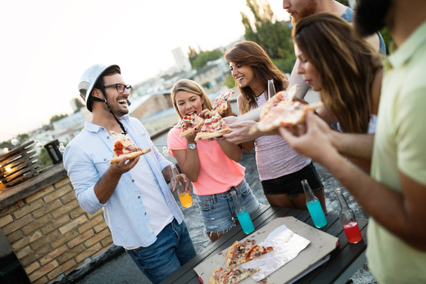 Friends and pizza. Group of young cheerful people eating pizza and having fun - Zdjęcie, obraz