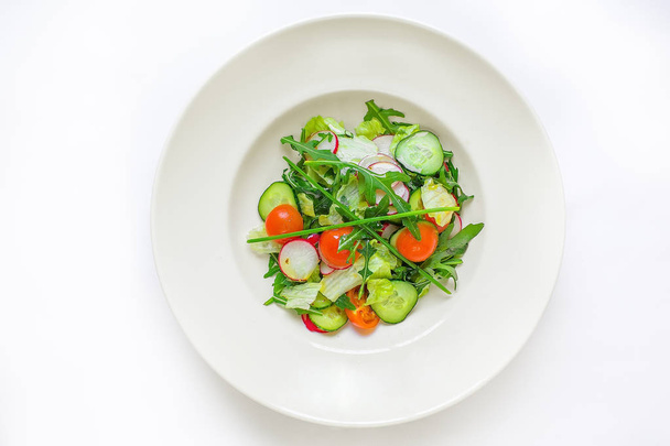 large plate with various kinds of tropical fruit flowers. Food for vegetarians, vegans and raw foodists. On a white plate - salad, arugula, apple, cucumber, radish, onion, tomato. View from above - Foto, Bild