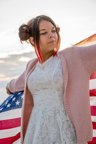 Teinityttö kietoutuu koko ajan Amerikan lipun ympärille.
 - Valokuva, kuva