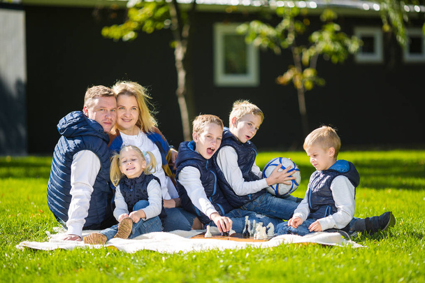 Big Family Relaxing In Green Nature. Happy family portrait on outdoor, group six people sit on grass, summer season, child and parent. Children, parenthood and nature concept. picnic outdoors on lawn - Photo, Image