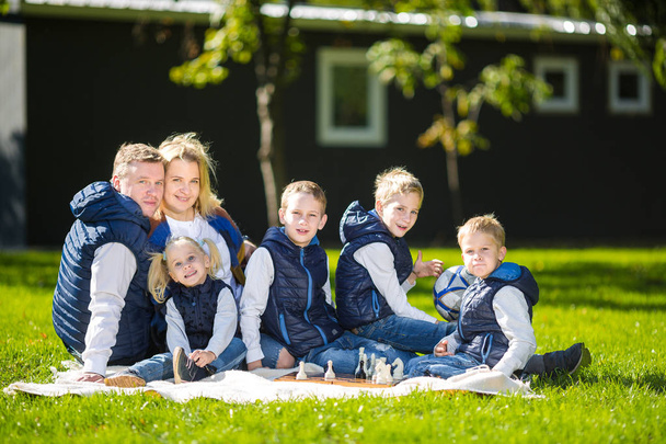 Big Family Relaxing In Green Nature. Happy family portrait on outdoor, group six people sit on grass, summer season, child and parent. Children, parenthood and nature concept. picnic outdoors on lawn - Photo, Image
