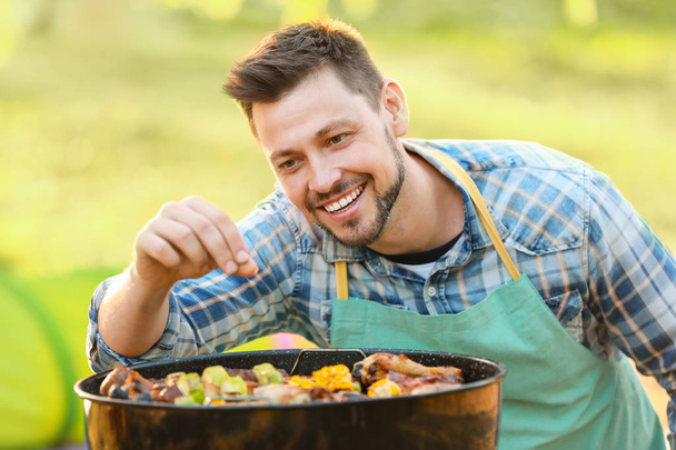 Homme cuisine des aliments savoureux sur barbecue grill en plein air
 - Photo, image
