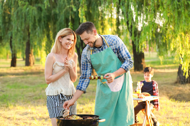 Gelukkig paar koken lekker eten op barbecue grill buitenshuis - Foto, afbeelding