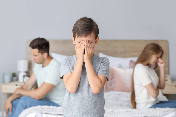 Sad little boy and his angry parents after quarrel in bedroom - Photo, Image