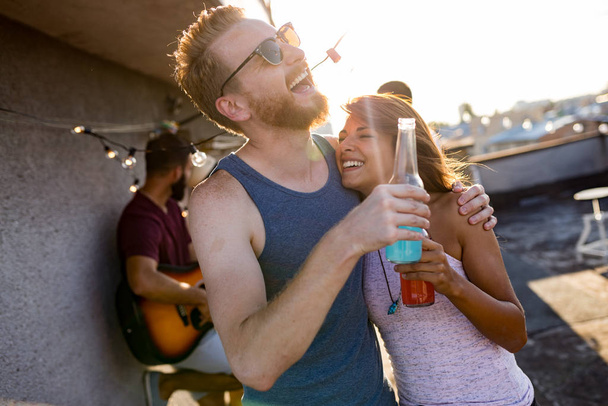 Cheerful young dancing couple having fun and enjoying party at summer - 写真・画像