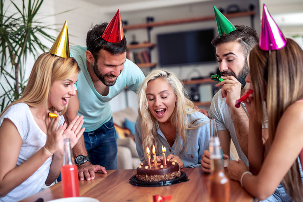 Μια ομάδα φίλων γιορτάζει τα γενέθλιά της στο σπίτι. Πάρτυ, διακοπές, ευτυχία, διασκέδαση και οι άνθρωποι έννοια. - Φωτογραφία, εικόνα