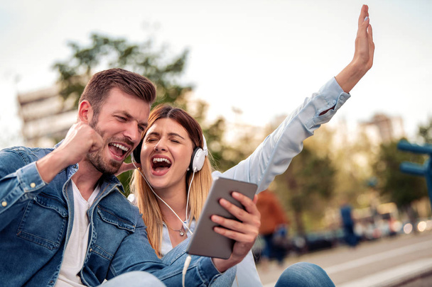 Dating.Young любящая пара слушает музыку с планшетами и наушниками
. - Фото, изображение