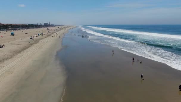 Letecký výhled na pláž se během slunečného dne těší. Huntington Beach, jihovýchodní Los Angeles, Kalifornie. USA - Záběry, video